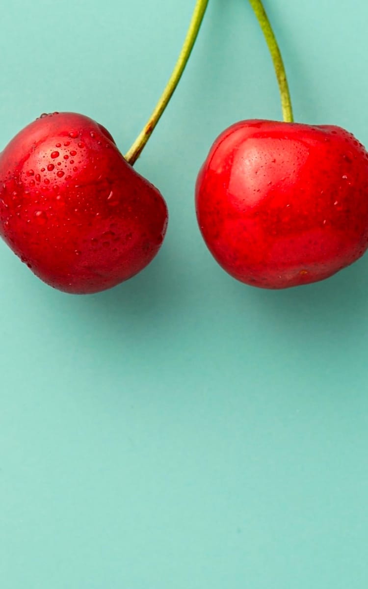 two cherries on green background